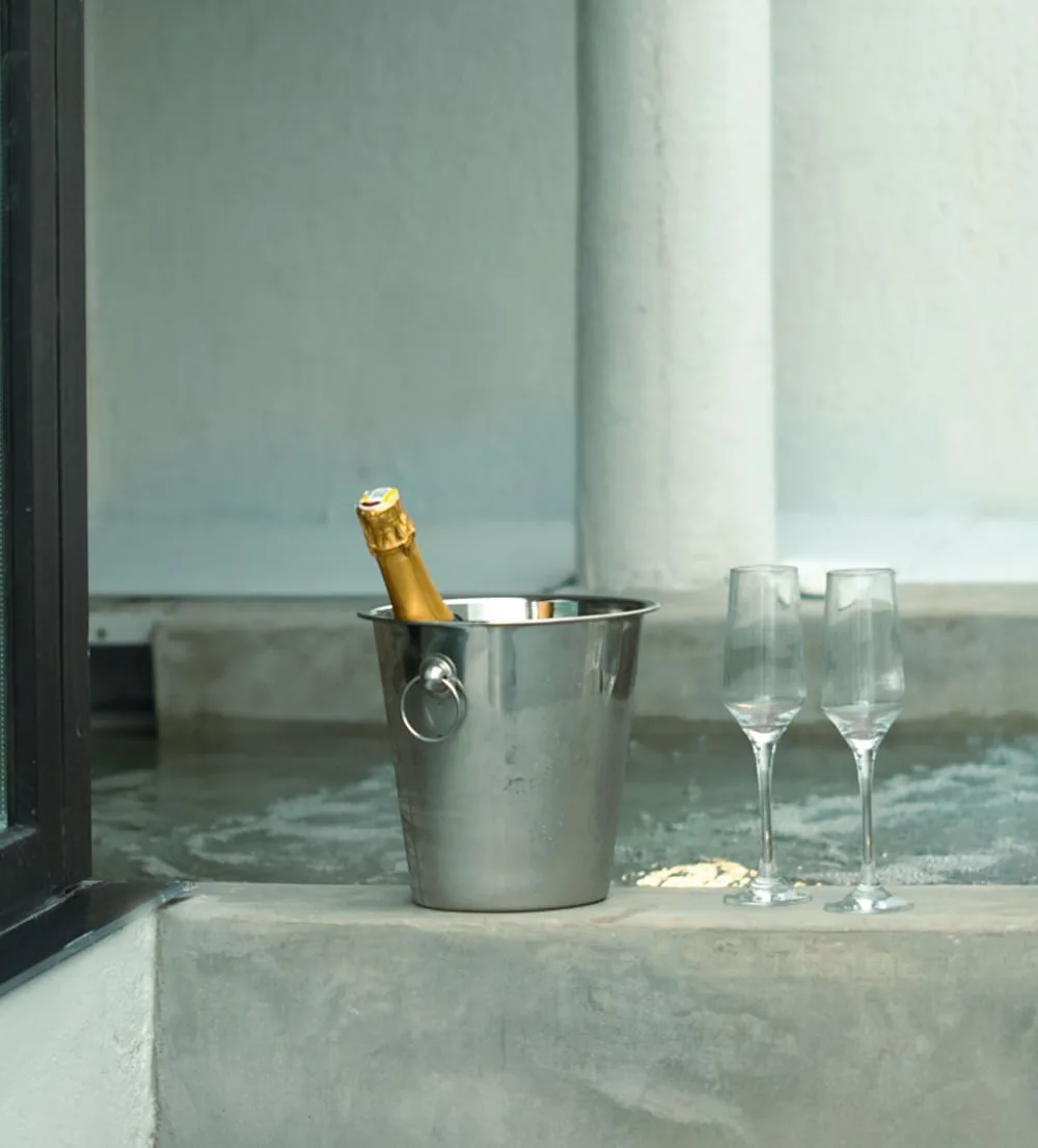 Champaña en hielo y dos copas al borde de la piscina privada de Mood Matuna Hotel