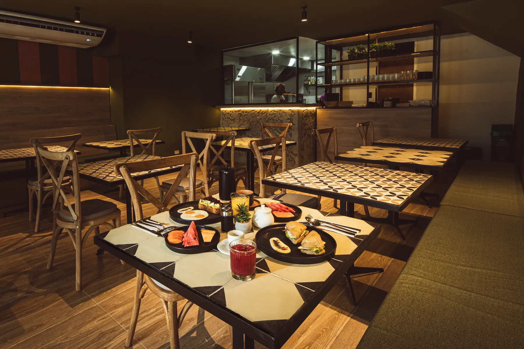 Salón del restaurante de Mood Matuna Hotel con cocina abierta y mesas de madera